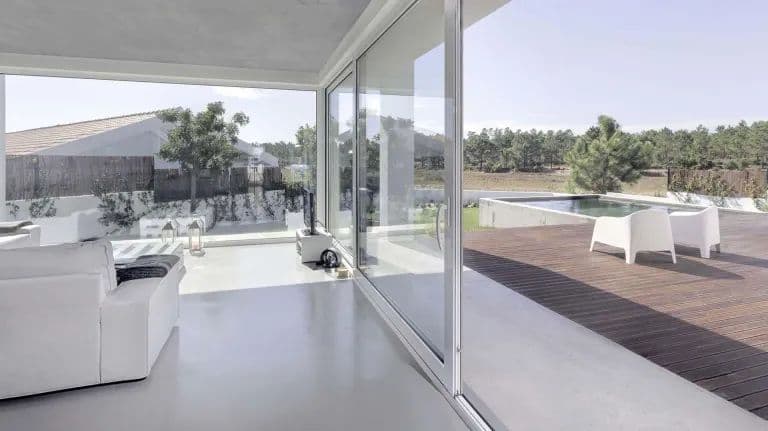 Soggiorno con parete vetrata continua aperta su un terrazzo con piscina